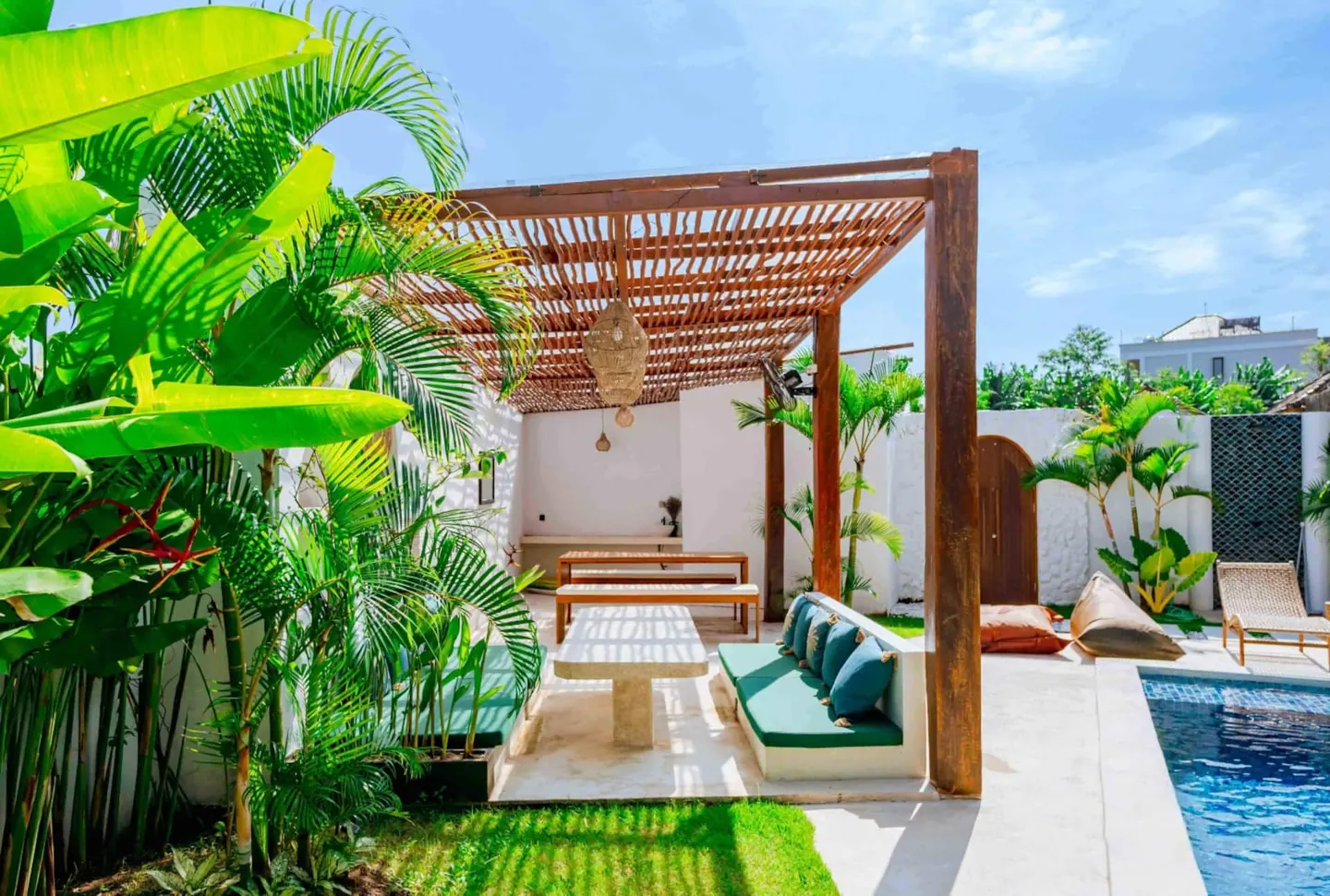 Outdoor dining pavilion and daybed lounge surrounded by tropical gardens with banana palms