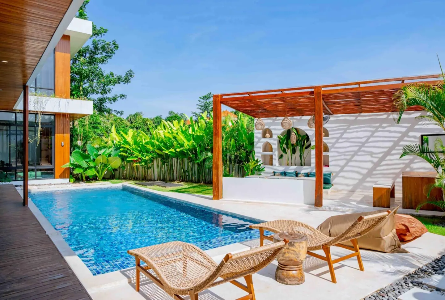 Private pool with custom teak pergola lounge, woven shade and an arched plaster daybed niche